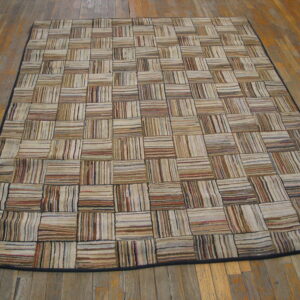 Patchwork rug featuring striped beige, tan, and brown squares displayed on distressed wood planks.