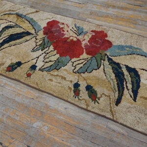 Shaggy tan runner featuring bold red flowers and dark blue leaves, placed on distressed wood plank flooring.