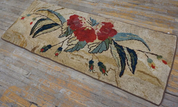 Shaggy tan runner featuring bold red flowers and dark blue leaves, placed on distressed wood plank flooring.