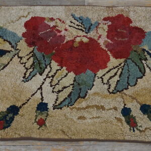 A shaggy beige rug with a vivid red, blue, and green floral bouquet on weathered wood.