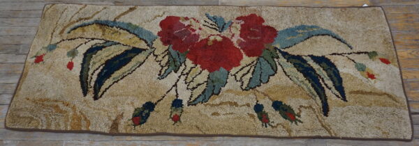 A shaggy beige rug with a vivid red, blue, and green floral bouquet on weathered wood.