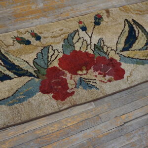 Shaggy beige rug featuring a detailed red, teal, and navy floral pattern on distressed wood flooring.