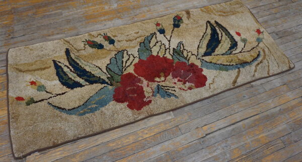 Shaggy beige rug featuring a detailed red, teal, and navy floral pattern on distressed wood flooring.