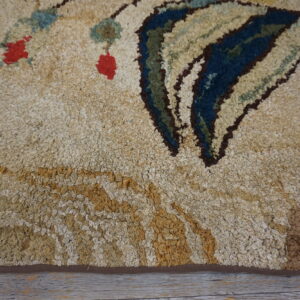 Close-up of a shaggy, beige rug with abstract blue, green, and red motifs, resting on gray wood planks.