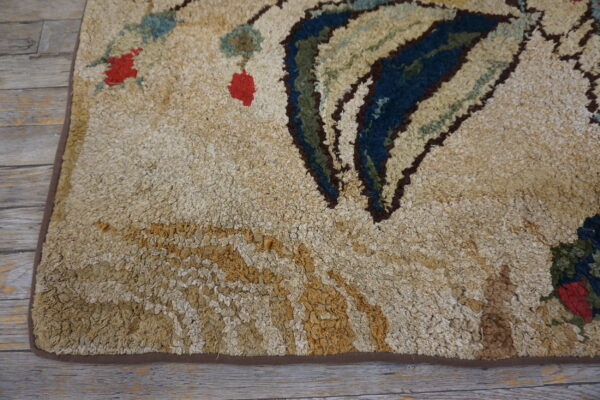 Close-up of a shaggy, beige rug with abstract blue, green, and red motifs, resting on gray wood planks.