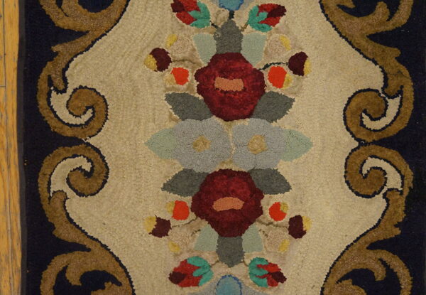 Looped rug detail with maroon floral medallions on beige, framed by brown scrolls and visible wood floor.