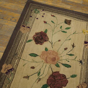 Low-pile tan runner rug with a maroon floral pattern and brown borders resting on aged wooden floorboards.