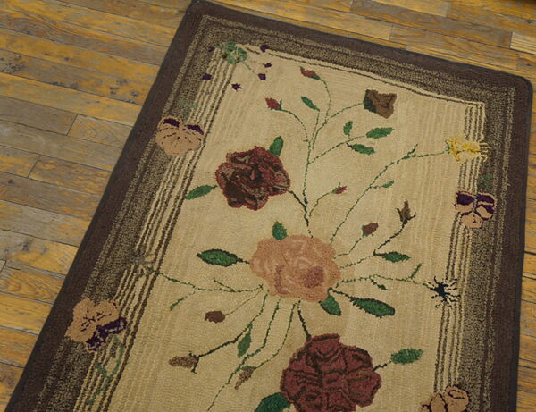 Low-pile tan runner rug with a maroon floral pattern and brown borders resting on aged wooden floorboards.