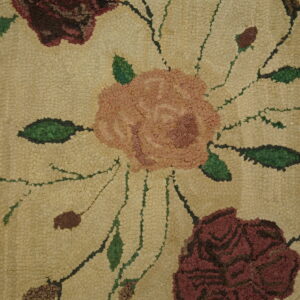 Bumpy texture of a hooked rug featuring pink and deep red roses on a tan field with green stems.