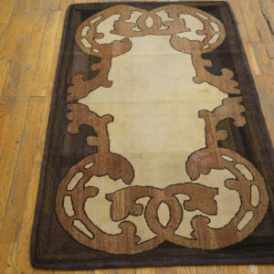 Ornate dark brown and tan scroll runner rug on worn light brown plank hardwood flooring.