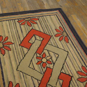 Textured rug featuring red floral and interlocking geometric patterns over vertical stripes on wood plank flooring.