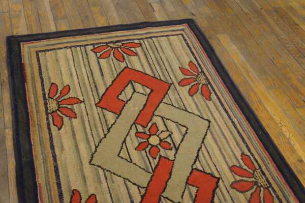 Textured rug featuring red floral and interlocking geometric patterns over vertical stripes on wood plank flooring.