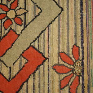 Highly textured rag rug featuring red and beige geometric floral designs next to a worn wooden floor.