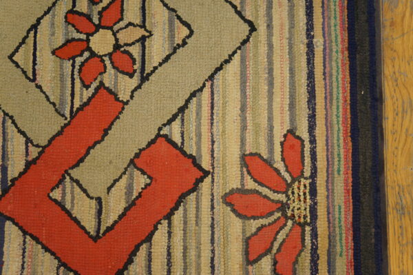 Highly textured rag rug featuring red and beige geometric floral designs next to a worn wooden floor.