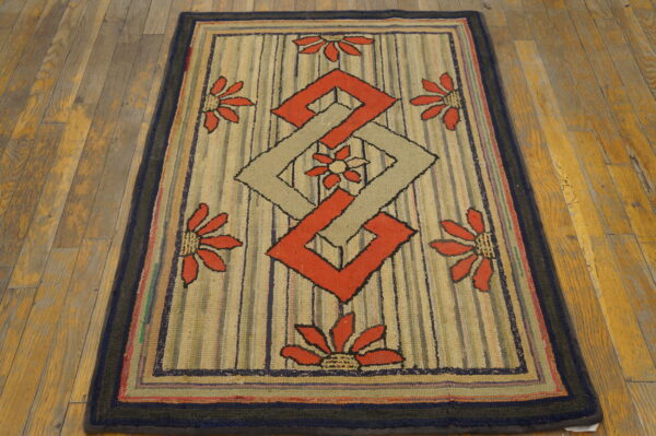 Low-pile rug with geometric and floral patterns in red and tan on a striped field over wood flooring.