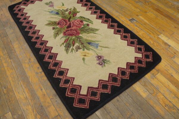 Beige rug with multicolored flowers, a maroon and black geometric border, sits on rustic wood.