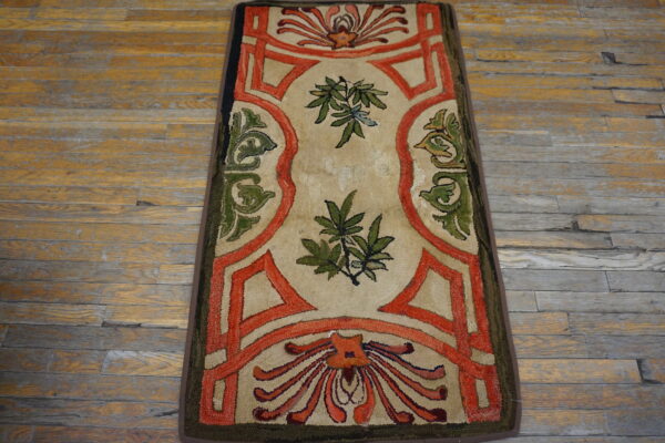Beige runner with bold orange borders and green floral motifs on distressed wood flooring.