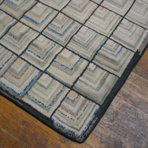Chunky textured rug featuring a muted neutral and blue concentric square pattern rests on a distressed wood floor.