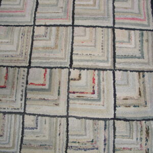 A pale log cabin grid rug with light gray, cream, and pink concentric squares on a wood floor.