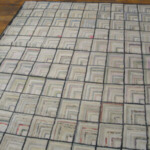 Light geometric rug with dark gray grid lines and textured squares on brown hardwood floor.