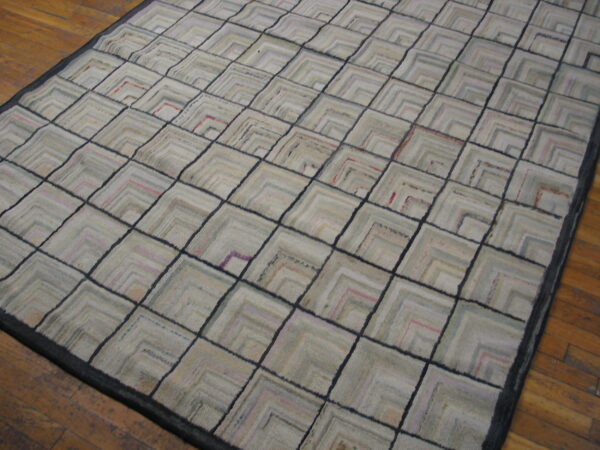 Muted neutral rug featuring a dark-lined diamond grid and internal chevron patterns on wood plank flooring.