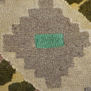 Nubby looped rug detail showing a geometric pattern in brown, cream, rust, and bright green.