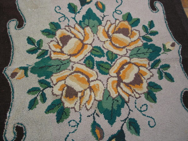 Highly textured rug detail showing gold and cream roses, green leaves, and a dark brown scalloped border.