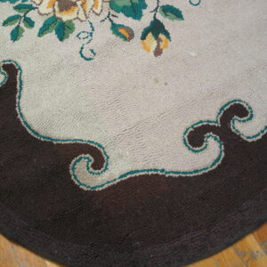 Textured rug detail showing a dark brown border and scalloped light center with floral accents.