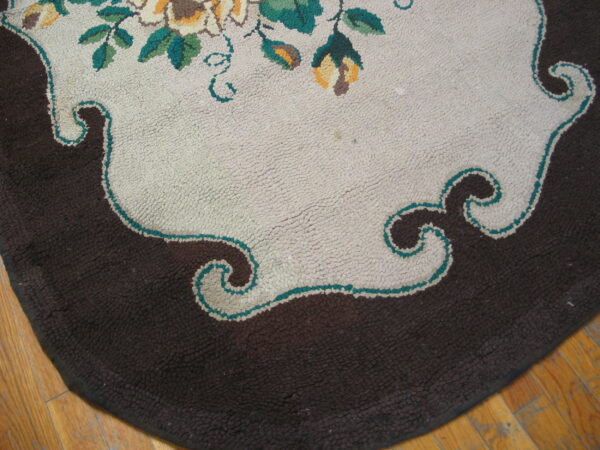 Textured rug detail showing a dark brown border and scalloped light center with floral accents.
