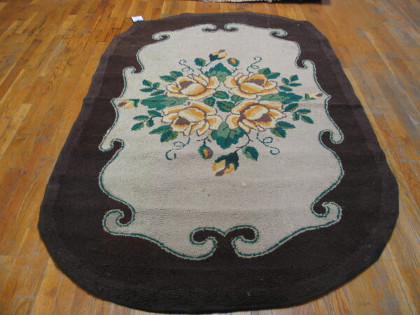 Shaped hooked rug in dark brown and tan with yellow floral design on light wood floorboards.