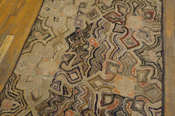 Abstract textured rug with variegated beige, gray, red, and navy accents rests on hardwood flooring.