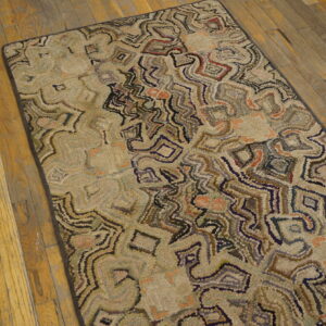 Muted, multi-color rug with abstract shapes and nubby texture rests on distressed wood flooring.