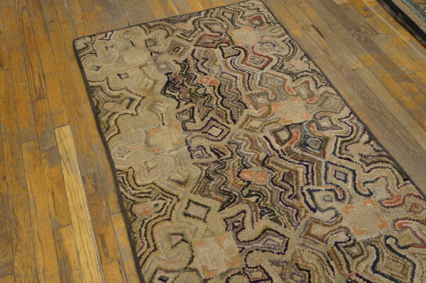 Muted, multi-color rug with abstract shapes and nubby texture rests on distressed wood flooring.