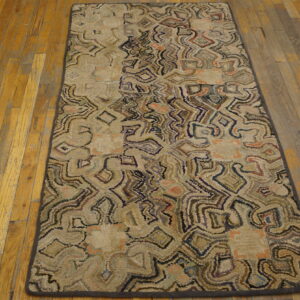Beige hooked runner rug with winding abstract patterns in brown, purple, and peach colors on a worn wood floor.