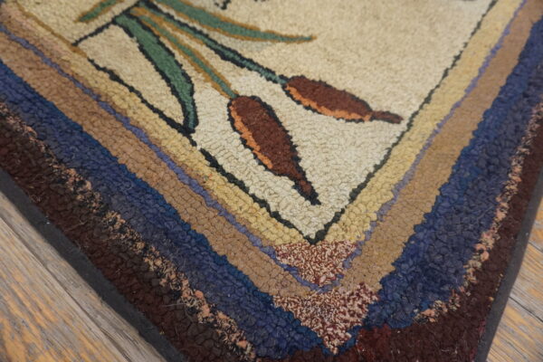 Chunky hooked rug detail showing brown cattails, green stems, and multicolored striped edges on wood planks.