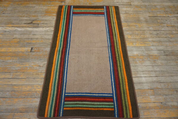 Runner rug with a solid tan field framed by vibrant vertical and horizontal multicolored stripes on wood flooring.