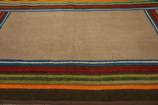 Looped beige rug featuring a striped border of blue, red, green, and orange colors.