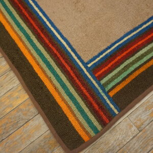 Beige textured rug corner featuring borders of multicolor stripes on distressed wood planks.