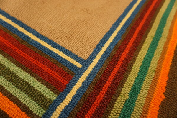 Detailed view of a thick, textured rug showing a tan field intersecting with multicolored vertical stripes.