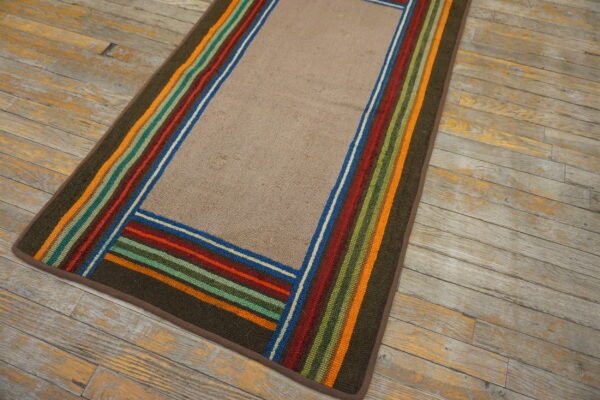 Textured beige runner rug framed by olive green and multi-colored stripes rests on weathered wood planks.