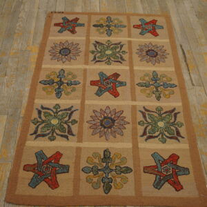 Textured tan rug displays a grid pattern of colorful floral and star designs on weathered wood floorboards.