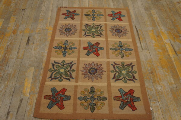 Textured tan rug displays a grid pattern of colorful floral and star designs on weathered wood floorboards.
