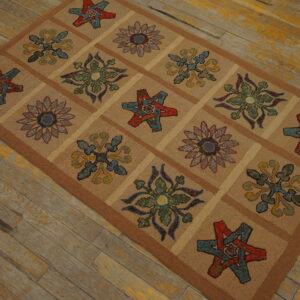 Low-pile tan rug with a colorful grid of floral and star motifs bordered in brown, resting on distressed wood planks.