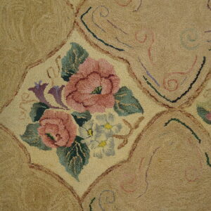 Textured beige rug with repeating panels containing pink and green floral bouquets and swirling accents.