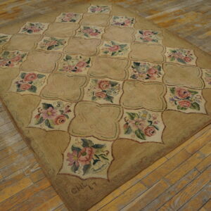 Tan and rose floral rug featuring a quatrefoil trellis pattern rests on distressed wooden plank flooring.