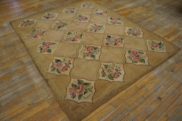 Tan and rose floral rug featuring a quatrefoil trellis pattern rests on distressed wooden plank flooring.