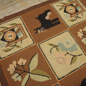 Looped pile rug with brown and beige squares containing stylized botanical and black animal motifs on rustic wood flooring.