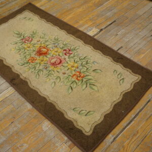 Low-pile beige accent rug with a bright floral bouquet and a dark brown border on weathered wood flooring.