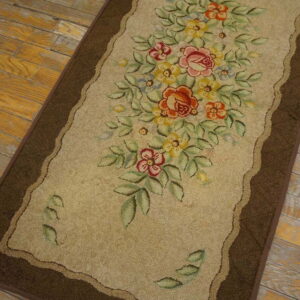 Beige runner rug with a bright floral bouquet and a brown border rests on rustic wood floors.
