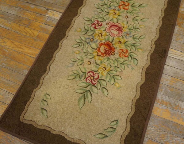 Beige runner rug with a bright floral bouquet and a brown border rests on rustic wood floors.